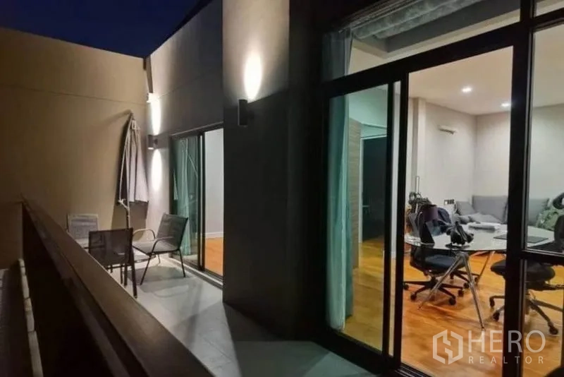 独立式住宅 出租 - 夜景阳台，壁灯、户外椅与伞，推拉玻璃门连接室内空间.