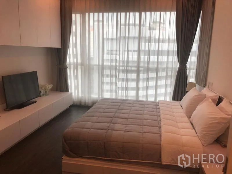 คอนโด ให้เช่าในPathum Wan, Bangkok - ห้องนอนหลัก เตียงควีน ตู้วางทีวี และหน้าต่างสูงจรดเพดาน