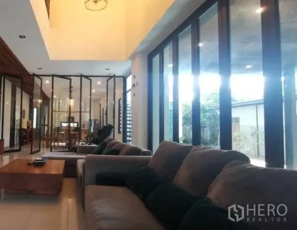 独立式住宅 出售在Pak Kret, Nonthaburi - 沙发区面向落地推拉门，挑高天花与采光充足。