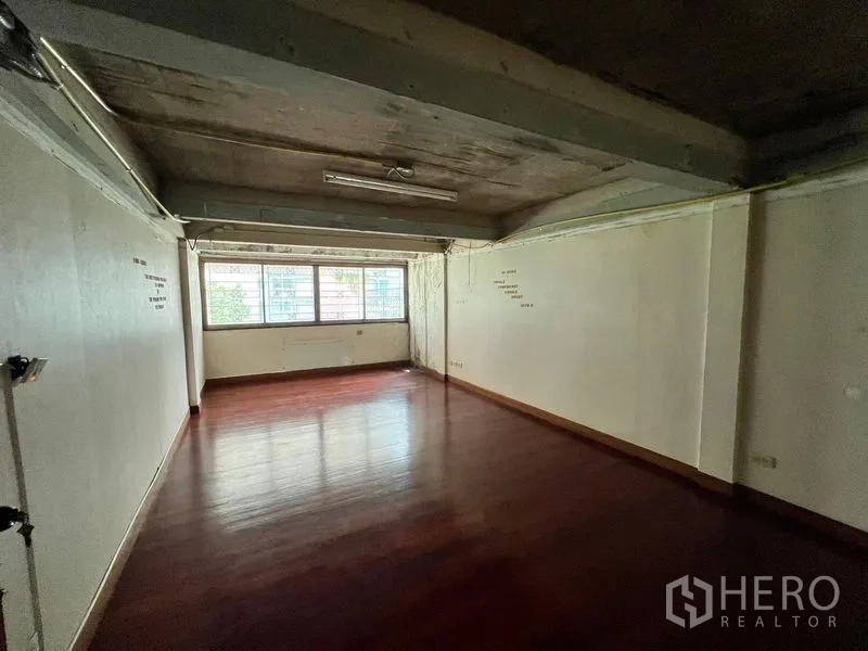 Townhouse for rent in Khlong Toei, Bangkok - Long multipurpose room with wooden floor and natural light from end windows.