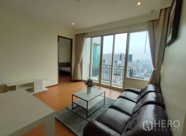 Condominium for rent in Chatuchak, Bangkok - Living room opening to a balcony with city view and a doorway to the bedroom.