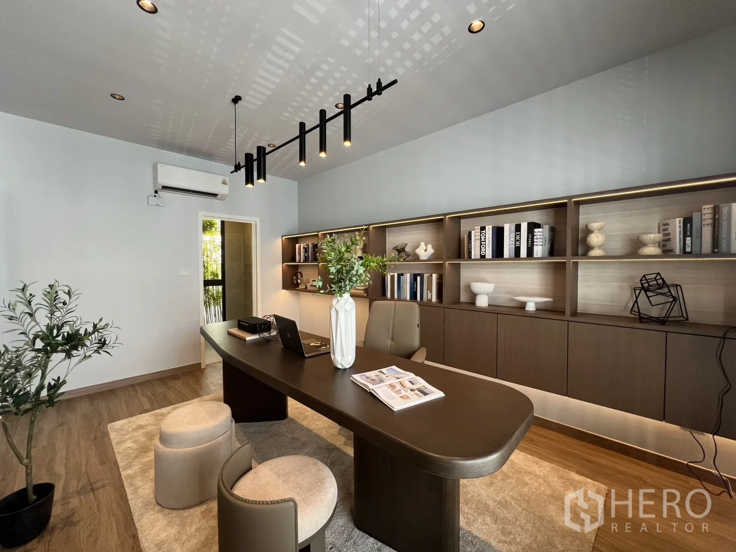 Townhouse for rent in Mueang Samut Prakan, Samut Prakan - Modern home office with long worktable, built-in illuminated shelves, and air conditioning.