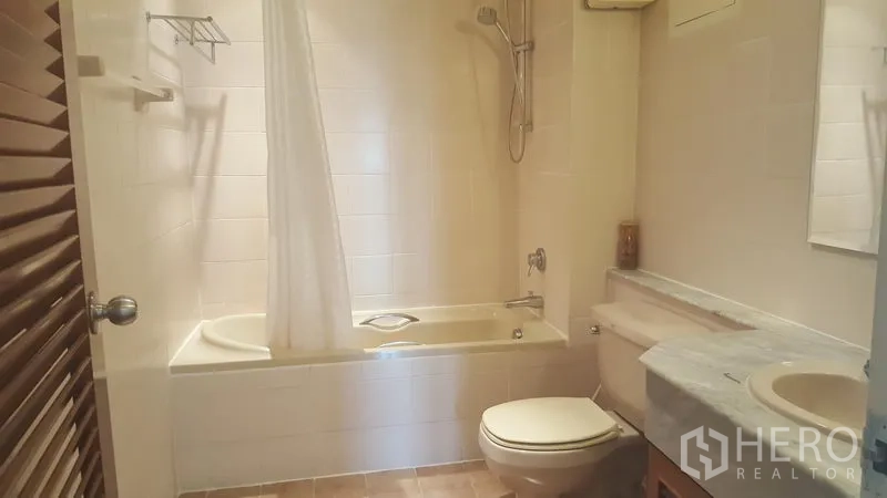 Condominium for rent in Watthana, Bangkok - Clean bathroom with bathtub and shower, marble-top vanity, toilet and tiled walls.