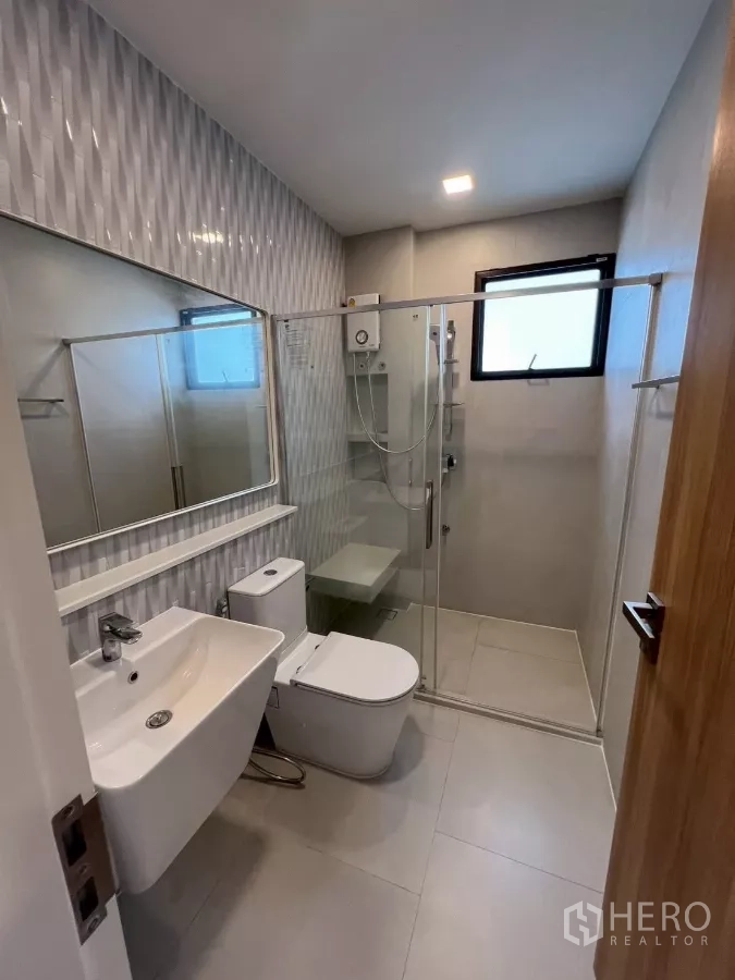 Detached House for rent in Samut Prakan - Bathroom with glass shower enclosure and textured feature tiles.