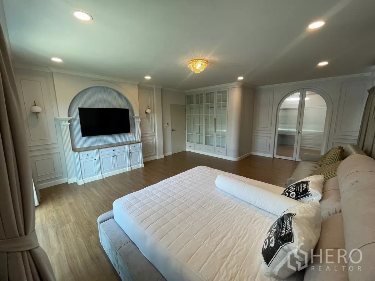 独立式住宅 出租在Bang Phli, Samut Prakan - 宽敞主卧，电视墙、拱形装饰与玻璃衣柜。