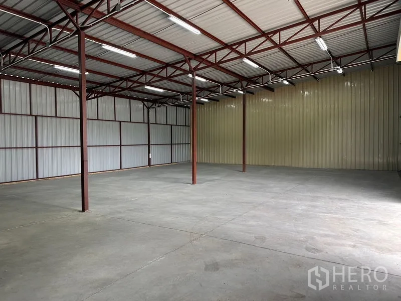 Warehouse for rent in Mueang Nonthaburi, Nonthaburi - Clear-span warehouse hall with metal cladding, roof trusses, and even lighting over a large concrete floor.