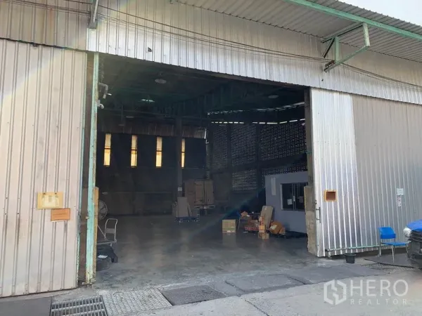货栈 出租在Mueang Pathum Thani, Pathum Thani - 金属滑门开启的高挑仓库，混凝土地面、天窗与内部小办公室。