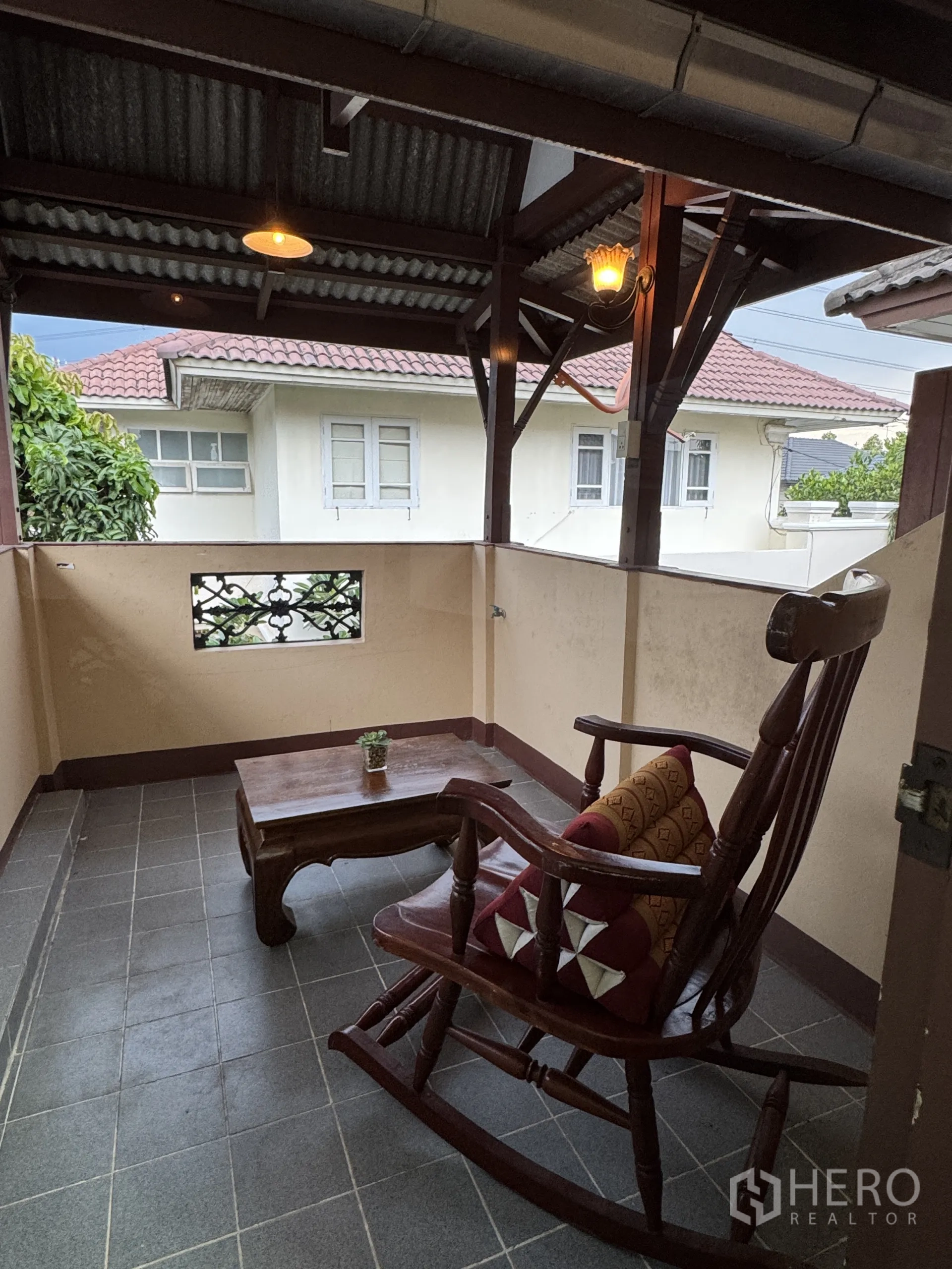 บ้าน ให้เช่าในMin Buri, Bangkok - ระเบียงชั้นบนแบบคลุมหลังคา พร้อมเก้าอี้โยกไม้และโต๊ะกลาง