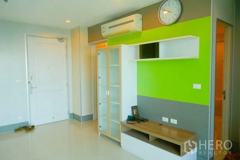 คอนโด ให้เช่าหรือขายในKhlong San, Bangkok - ผนังทีวีในห้องนั่งเล่นพร้อมตู้โชว์กระจก ชั้นวาง และแอร์แบบสplit