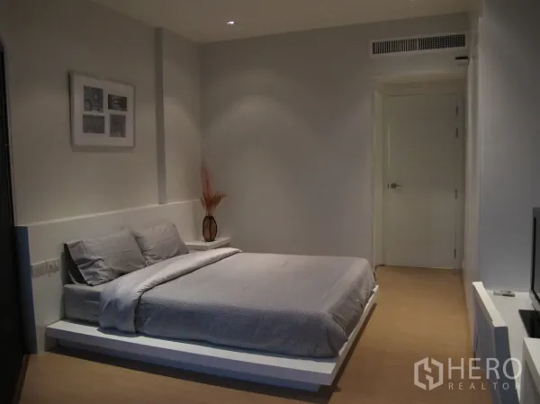 Condominium for rent in Watthana, Bangkok - Minimalist second bedroom with low platform bed, wall art and neutral tones.