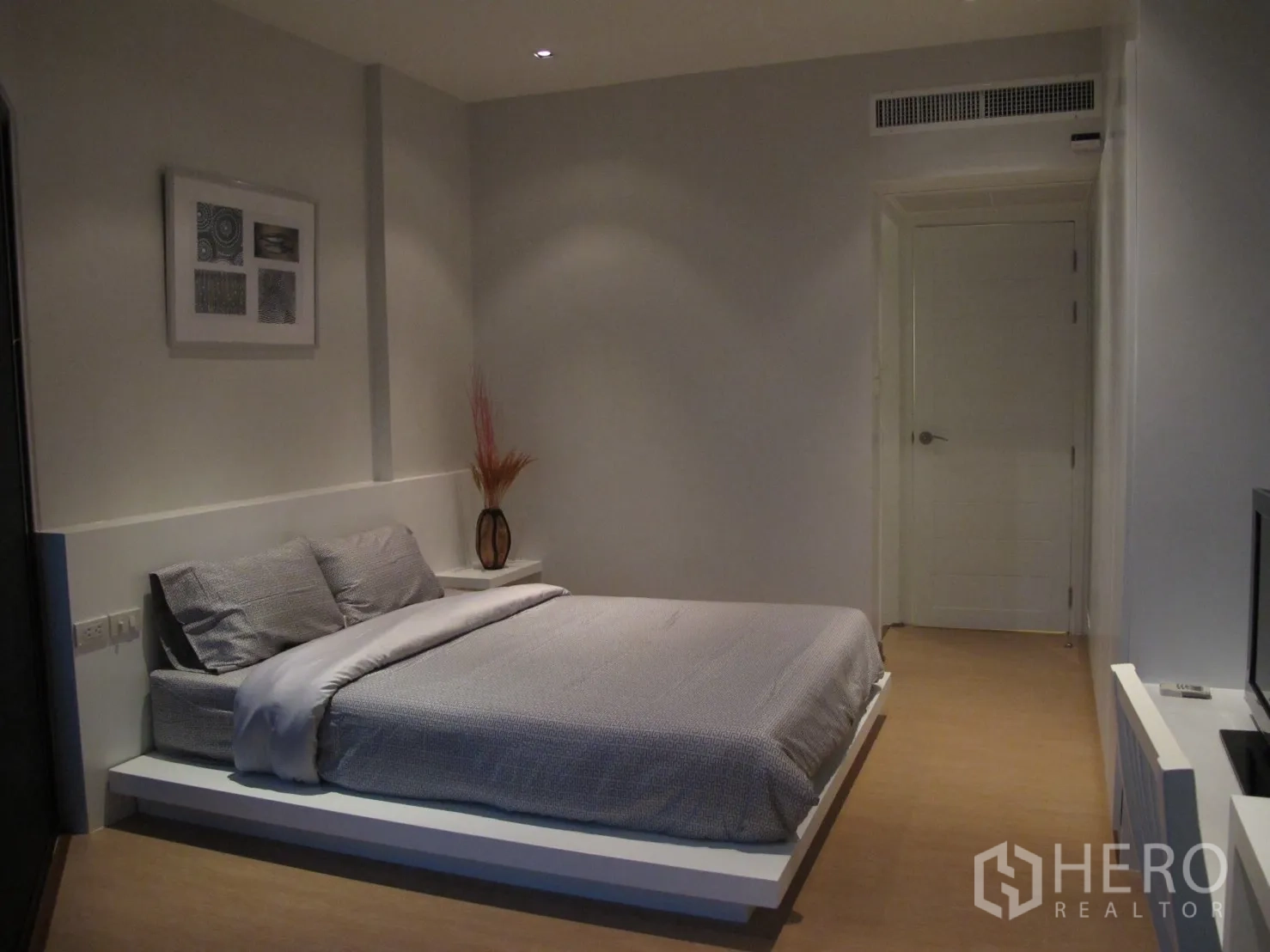Condominium for rent in Watthana, Bangkok - Minimalist second bedroom with low platform bed, wall art and neutral tones.