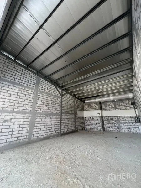 零售空间 出租在Khlong Toei, Bangkok - 商铺室内毛坯，裸露砖墙、钢结构屋顶与水泥基层地面。