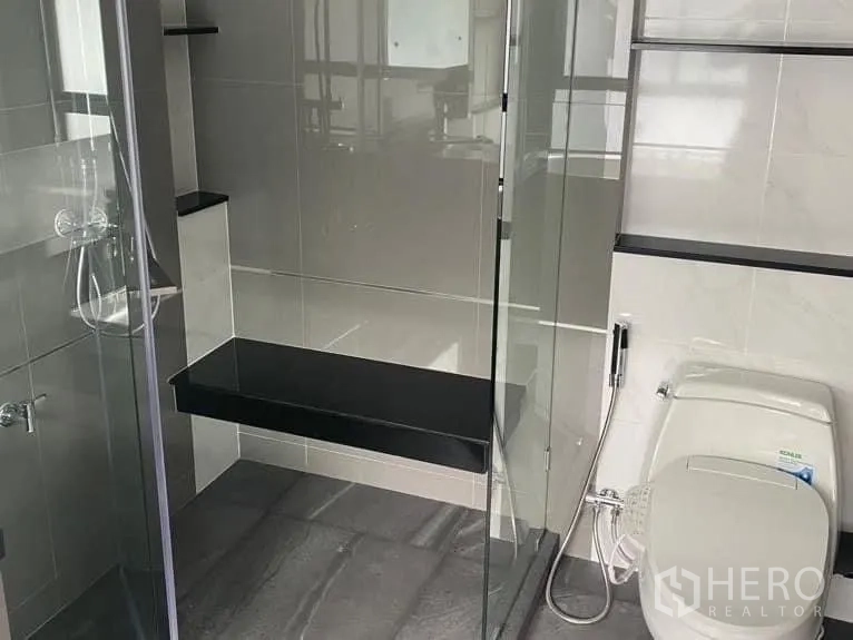 Detached House for rent in Bang Kapi, Bangkok - Modern bathroom featuring glass-enclosed shower with bench and toilet.