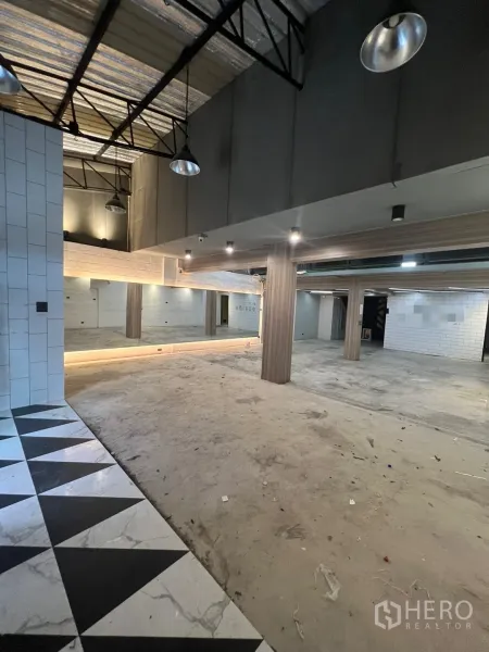 พื้นที่ขายปลีก ให้เช่าในPhaya Thai, Bangkok - พื้นที่ชั้นล่างแบบโอเพ่นสเปซ เพดานสูง โครงเหล็ก ผนังกระจกเงา เสาไม้ และพื้นกระเบื้องลายสามเหลี่ยม.