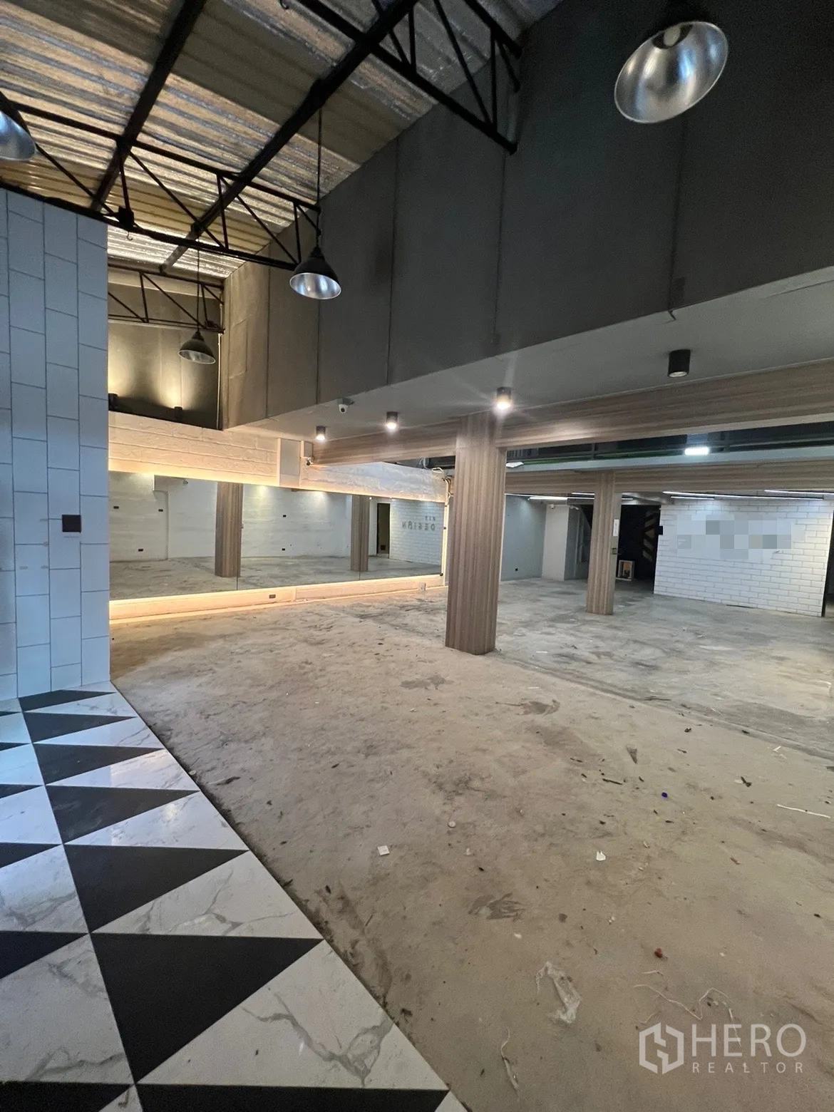 พื้นที่ขายปลีก ให้เช่าในPhaya Thai, Bangkok - พื้นที่ชั้นล่างแบบโอเพ่นสเปซ เพดานสูง โครงเหล็ก ผนังกระจกเงา เสาไม้ และพื้นกระเบื้องลายสามเหลี่ยม.