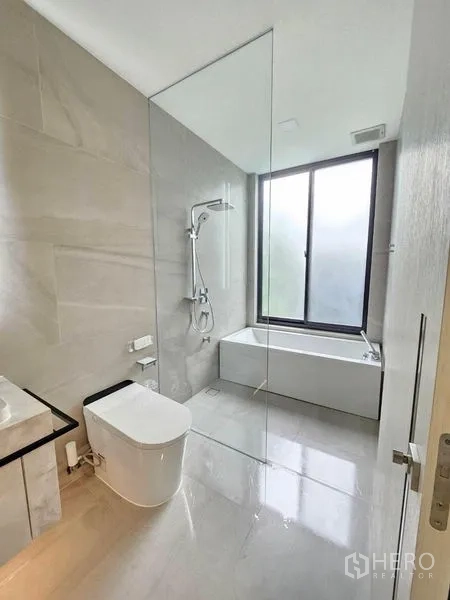 Detached House for rent - Bathroom with glass shower partition, bathtub and a large frosted window.