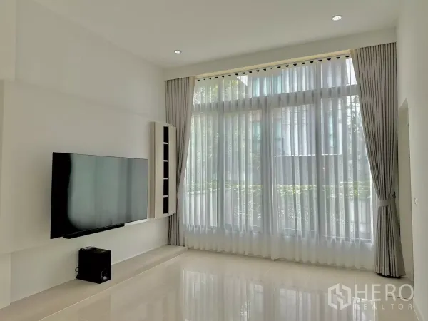 บ้าน ให้เช่าหรือขายในPrawet, Bangkok - ห้องนั่งเล่นเพดานสูงโปร่ง ผ้าม่านเต็มผืน และทีวีแขวนผนัง