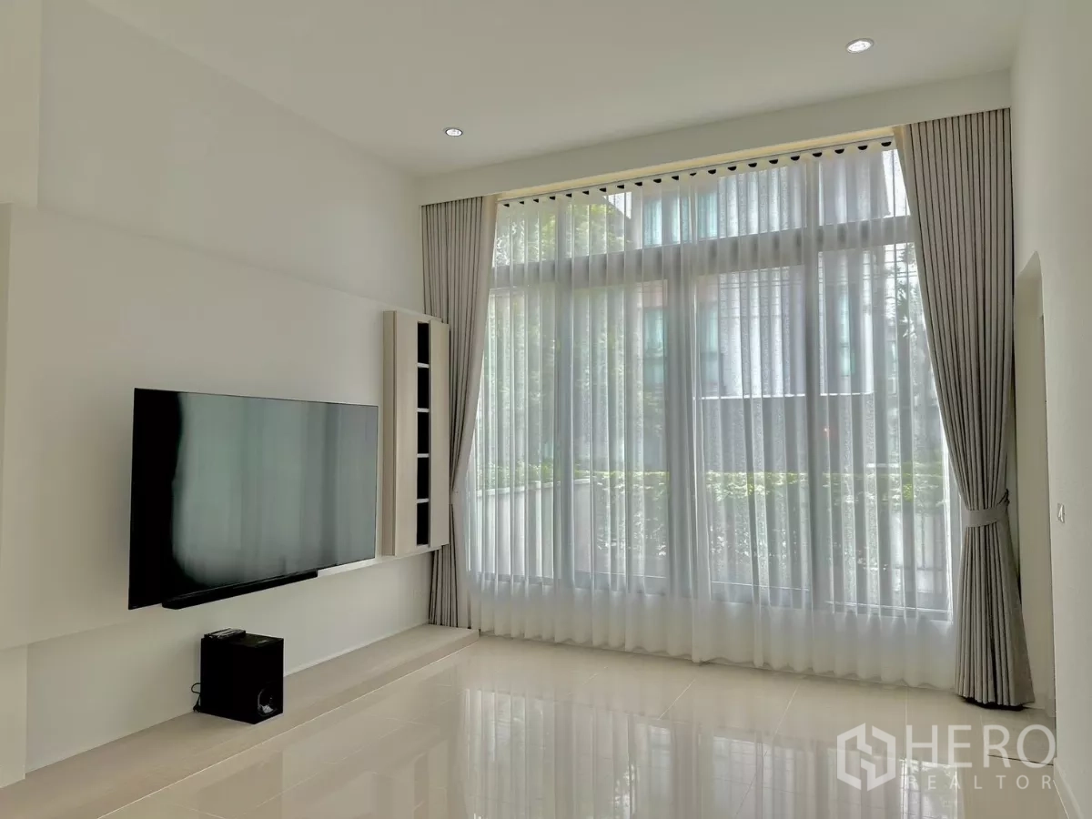 บ้าน ให้เช่าหรือขายในPrawet, Bangkok - ห้องนั่งเล่นเพดานสูงโปร่ง ผ้าม่านเต็มผืน และทีวีแขวนผนัง