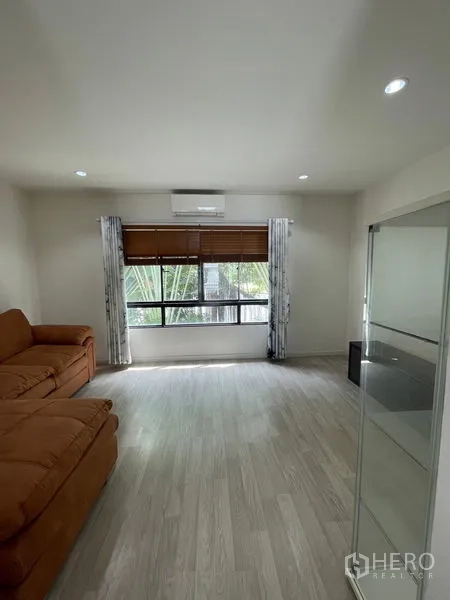 Townhouse for rent in Bang Kapi, Bangkok - Bright living area with large window, blinds, air conditioner and pale wood floors.