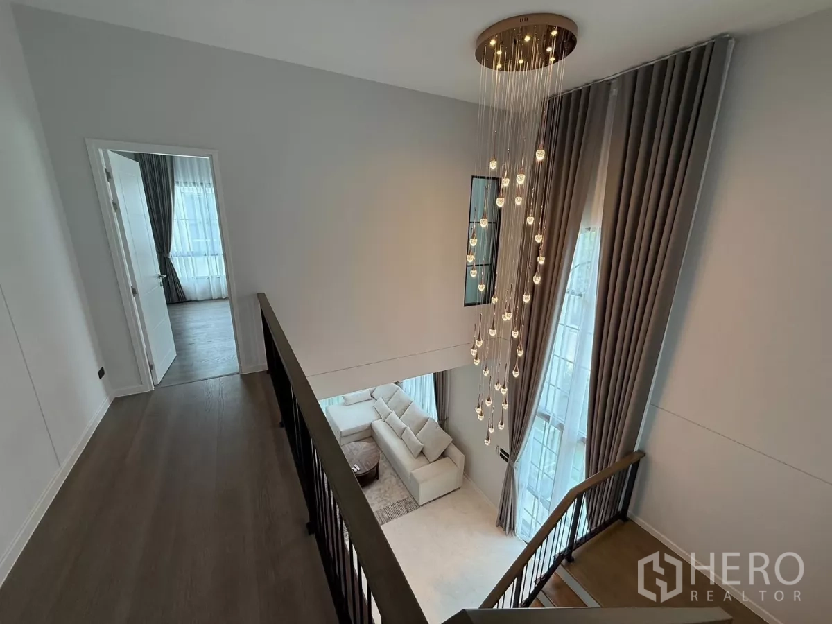 独立式住宅 出租或出售在Bang Phli, Samut Prakan - 从二层回廊俯瞰客厅，焦点吊灯与高帘营造大气感。