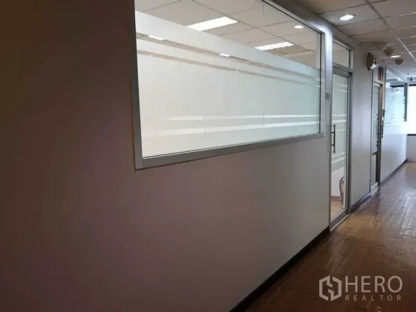 办公空间 出租在Watthana, Bangkok - 明亮的办公走廊，磨砂玻璃隔断、仿木地板与嵌入式灯光。