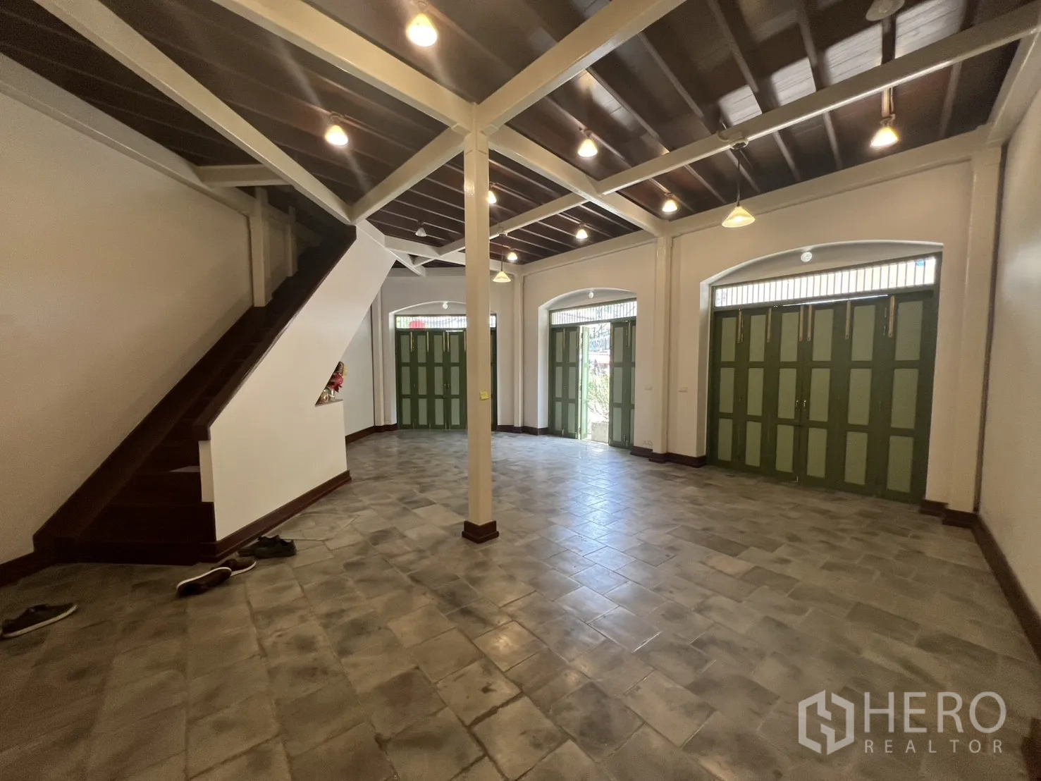 Shophouse for rent in Samphanthawong, Bangkok - Open-plan retail space with tiled floor, staircase to upper levels and multiple green shuttered doors for strong street exposure.