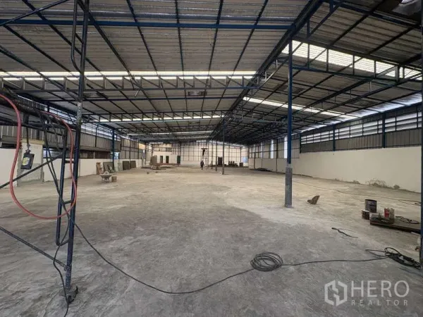 货栈 出租在Prawet, Bangkok - 仓库内部空间开阔，钢桁架屋顶配采光板与通风窗，地面为平整混凝土。