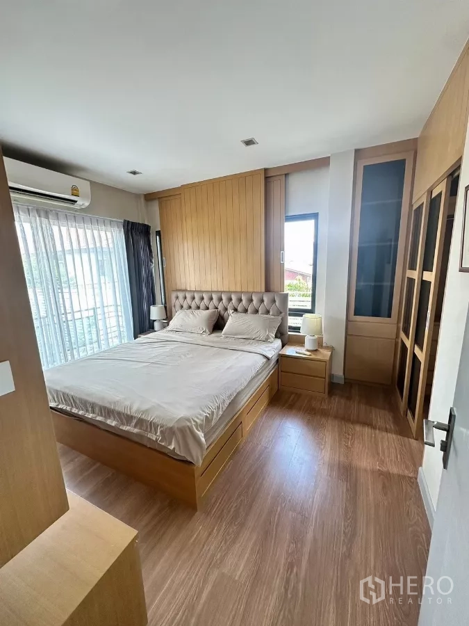 Detached House for rent in Saphan Sung, Bangkok - Master bedroom in daylight with large windows and custom wood paneling.