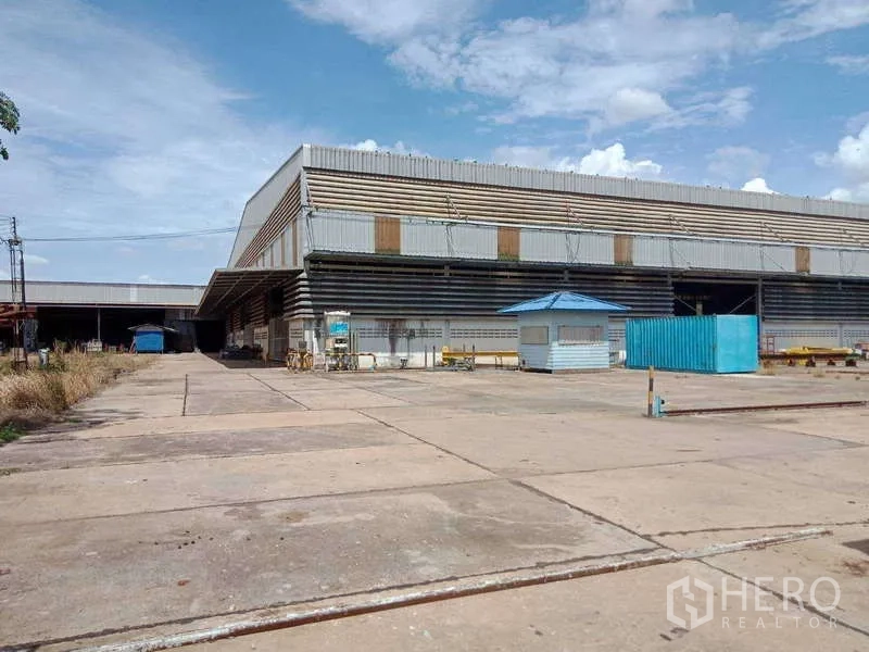 工厂 出售在Chachoengsao - 通往工厂立面的铺装道路，设有蓝色亭和集装箱。