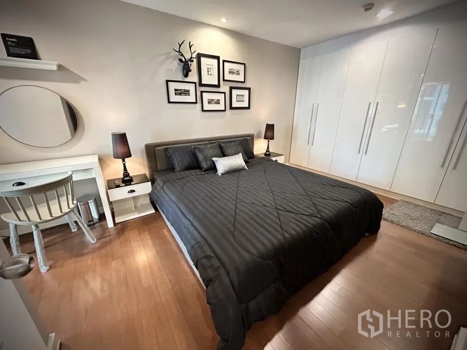 คอนโด for rent in Huai Khwang, Bangkok - ห้องนอนหลักเตียงคิงไซซ์ โต๊ะข้าง และตู้เสื้อผ้า