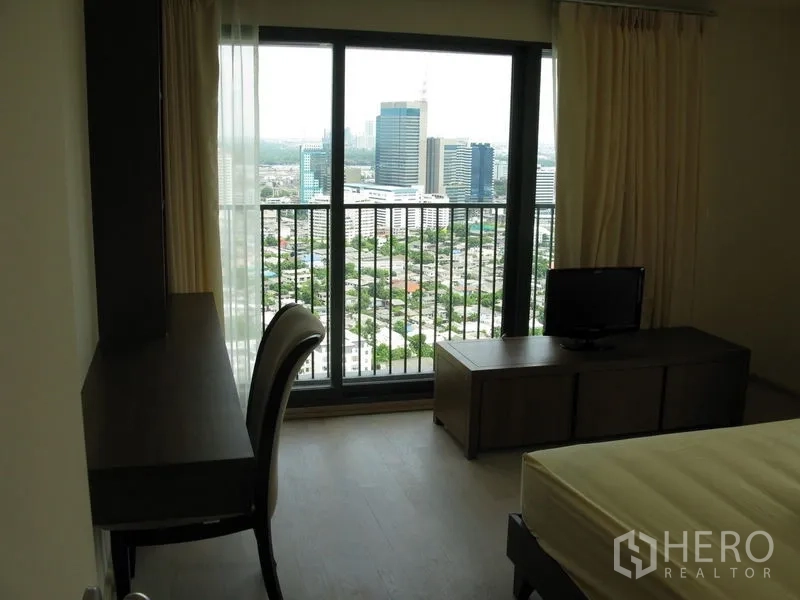 คอนโด ให้เช่าในKhlong Toei, Bangkok - ห้องนอนพร้อมโต๊ะทำงานและประตูกระจกเต็มบานออกสู่ระเบียงวิวเมือง
