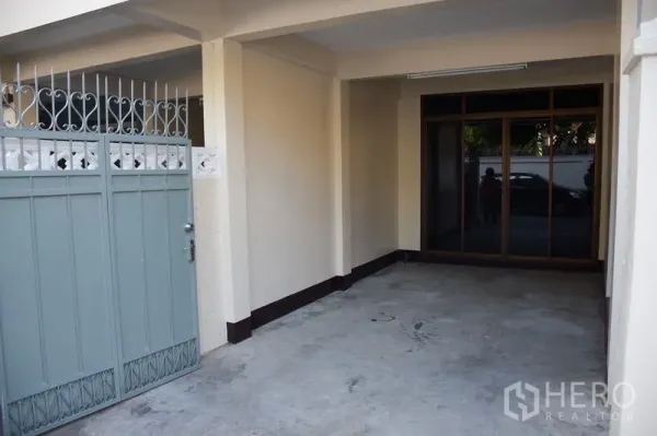 联排别墅 出租在Watthana, Bangkok - 推拉金属门后的有顶车位，通向玻璃入户门。