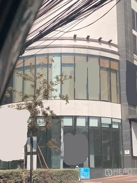 零售空间 出租在Watthana, Bangkok - 近景：零售店面玻璃幕墙、入口与人行道绿化。