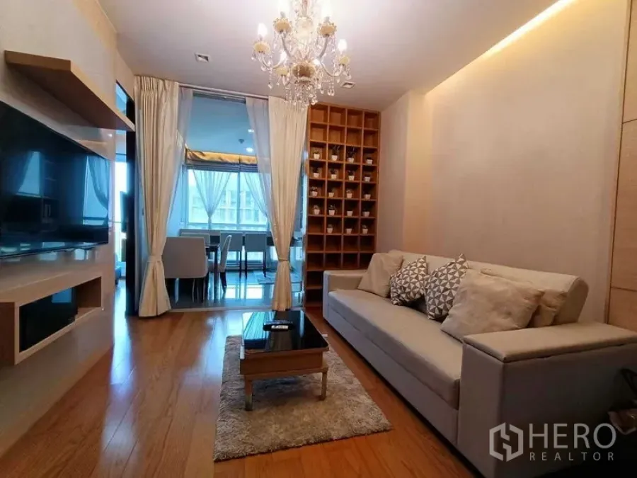 คอนโด ให้เช่าในRatchathewi, Bangkok - ห้องนั่งเล่นมองไปยังโซนรับประทานอาหารที่กั้นกระจก มีชั้นโชว์และโซฟาทันสมัย