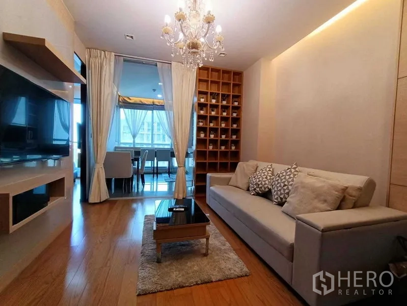 คอนโด ให้เช่าในRatchathewi, Bangkok - ห้องนั่งเล่นมองไปยังโซนรับประทานอาหารที่กั้นกระจก มีชั้นโชว์และโซฟาทันสมัย