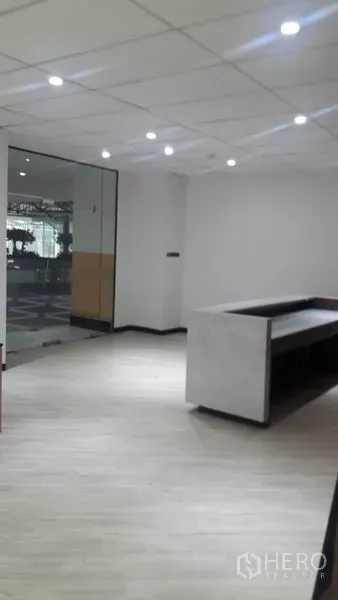 办公空间 出租在Huai Khwang, Bangkok - 从前台内看向玻璃入口，墙面素色并配有射灯。