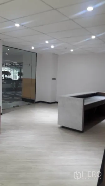 办公空间 出租在Huai Khwang, Bangkok - 从前台内看向玻璃入口，墙面素色并配有射灯。