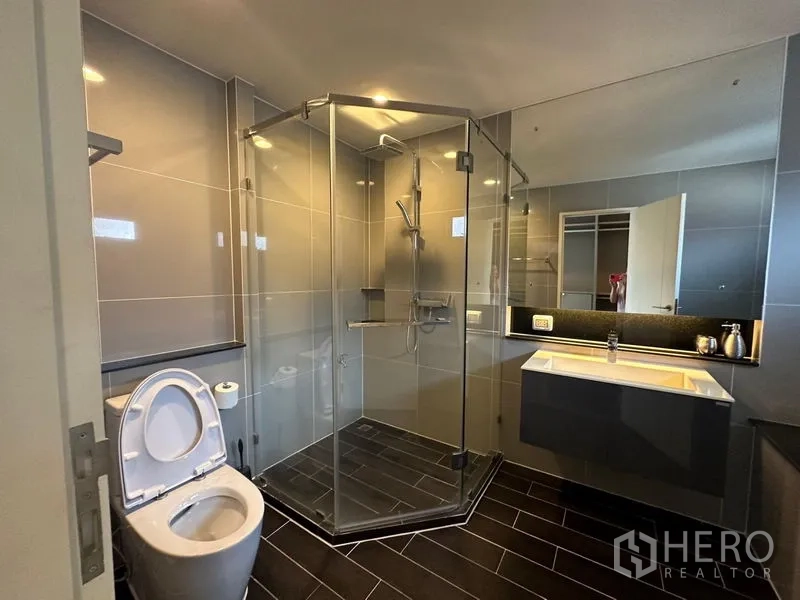 บ้าน ให้เช่าหรือขายในLam Luk Ka, Pathum Thani - ห้องน้ำสมัยใหม่พร้อมตู้กระจกกั้นอาบน้ำ อ่างล้างหน้า และโถสุขภัณฑ์พื้นกระเบื้องสีเข้ม