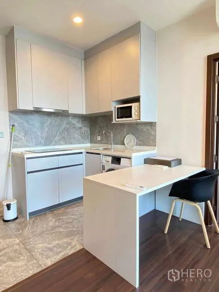 Condominium for rent - Modern L‑shaped kitchen with stone backsplash, built‑in microwave, washer and breakfast peninsula.