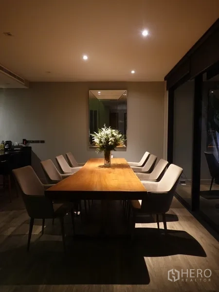 Semi-detached House for rent in Watthana, Bangkok - Dining room with a long wooden table and upholstered chairs.