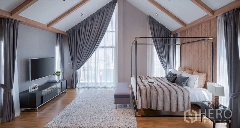 Detached House for sale in Lam Luk Ka, Pathum Thani - Spacious master suite featuring a vaulted ceiling, four-poster bed, TV console and tall drapes.
