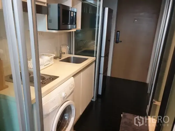 公寓 出租在Khlong Toei, Bangkok - 封闭式长廊厨房，配电磁炉、水槽、微波炉、冰箱与洗衣机。