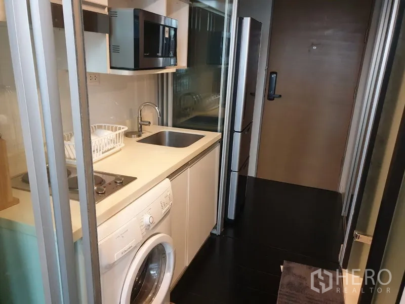 公寓 出租在Khlong Toei, Bangkok - 封闭式长廊厨房，配电磁炉、水槽、微波炉、冰箱与洗衣机。