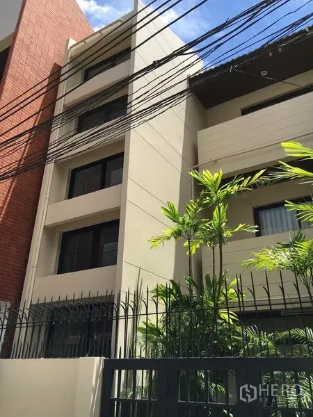 Townhouse for rent in Watthana, Bangkok - Modern multi-storey townhouse exterior with cream facade, large windows and a gated fence.