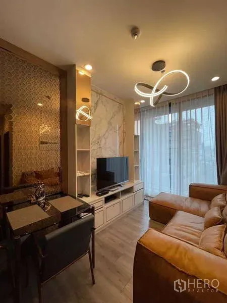 Condominium for rent - Living room with TV console, marble feature wall, balcony access, and contemporary ring ceiling lights above a tan leather sofa.