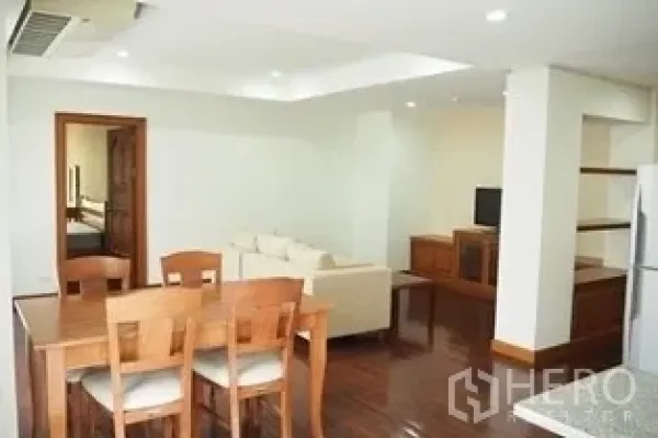 Condominium for rent in Pathum Wan, Bangkok - Open-plan dining and living area with wooden table and media cabinet.