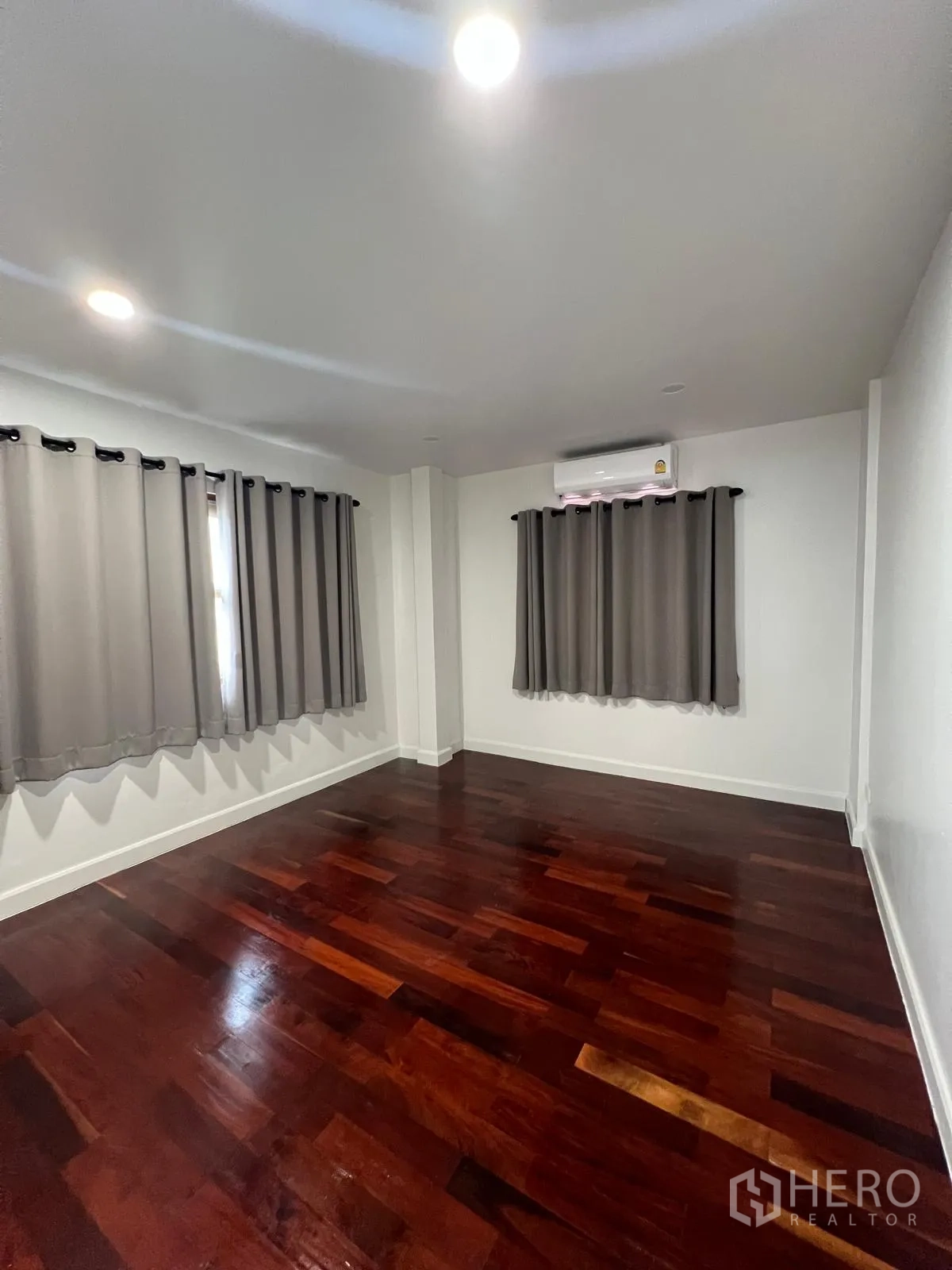 Detached House for rent in Saphan Sung, Bangkok - Bedroom featuring rich wooden flooring, gray drapes and a wall-mounted air conditioner.