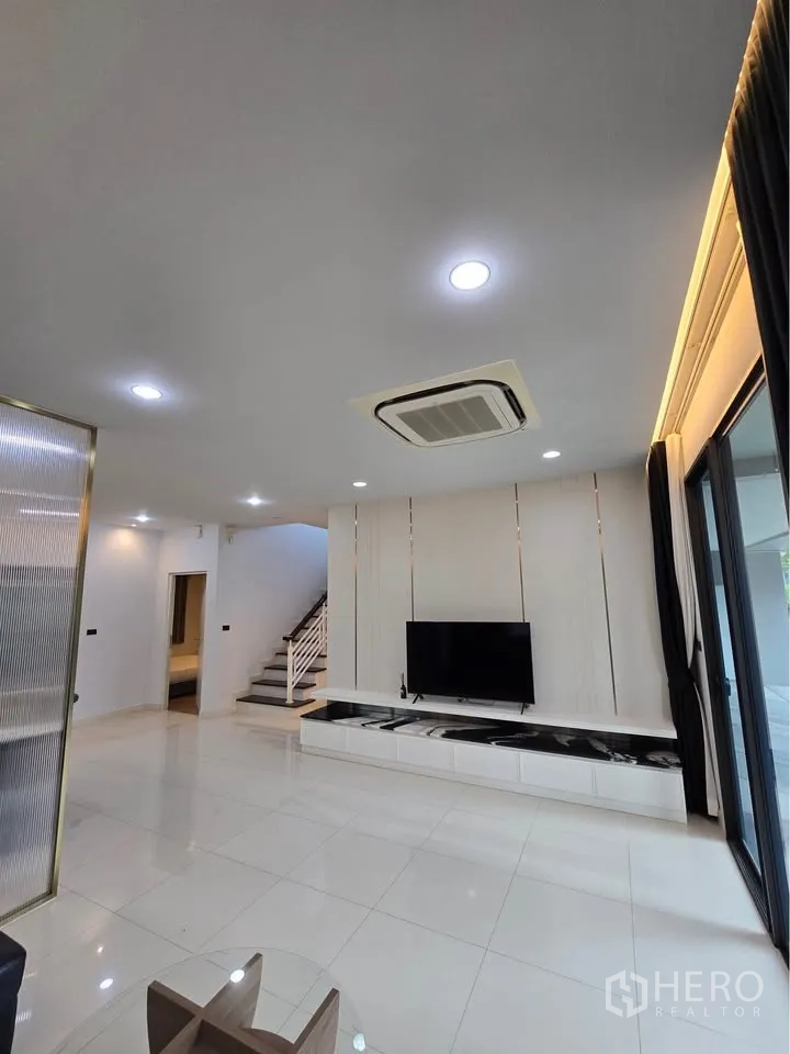 บ้านเดี่ยว for rent in Bang Kapi, Bangkok - ห้องนั่งเล่นผนังทีวีแบบบิวท์อินและบันไดขึ้นชั้นสอง