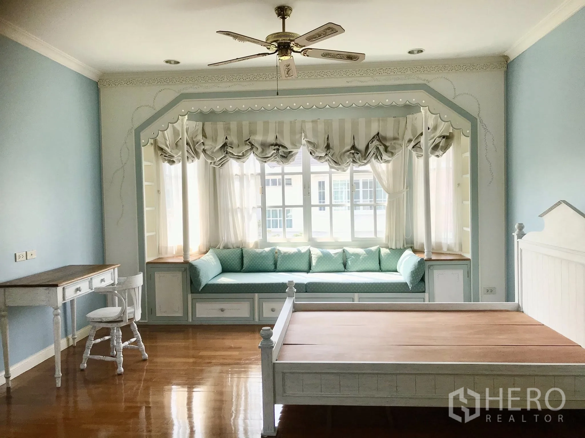 Detached House for rent in Mueang Samut Prakan, Samut Prakan - Spacious bedroom with pastel blue walls and a built-in window seat under a large bay window.