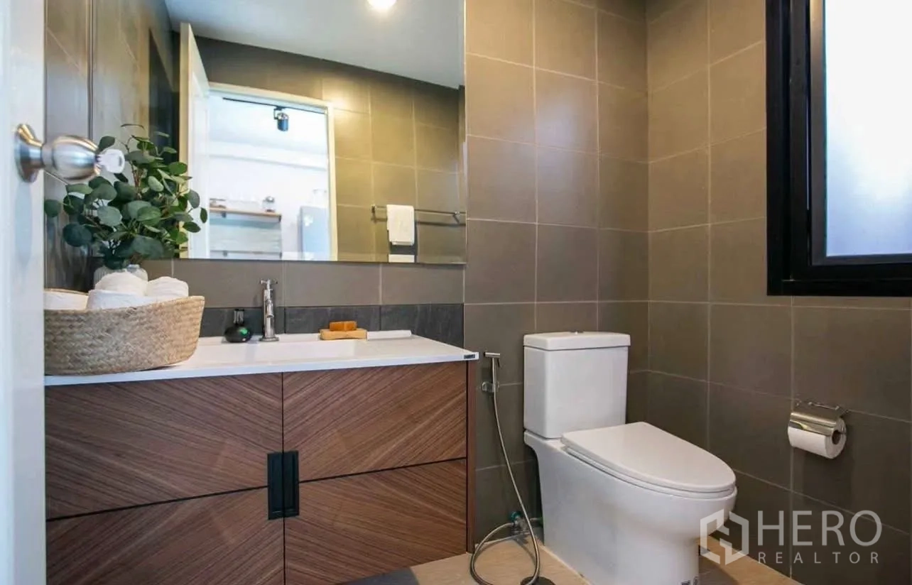 Townhouse for rent in Suan Luang, Bangkok - Modern bathroom with wood vanity, large mirror, toilet and frosted window.